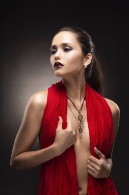 Kırmızı bir eşarp ile çıplak onun meme kapsayan ve modern bir kolye üzerinde derin dekolte giyen güzel esmer üstsüz kız modeli. Uzay kopyalayın. Reklam ve ticari tasarım. Sağlıklı temiz cilt
