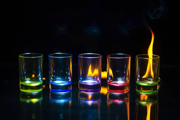 Five Multicolored Empty Shot Glasses Reflected Glass Surface Which Flame — Stock Photo, Image