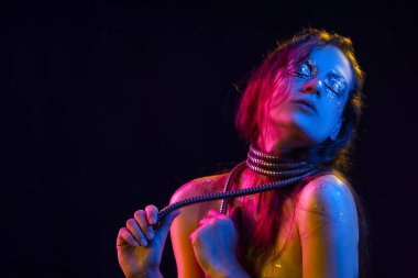 Cretative makyaj güzel kızla glitter yaşlarla, boynunu bir metalik spiral hortum ile pembe, mavi ve sarı ışıkla aydınlatılmış onun yüz tamamladı yaptı. Siyah izole. Kopya alanı.