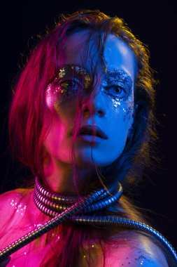Cretative makyaj güzel kızla glitter yaşlarla, boynunu bir metalik spiral hortum ile pembe, mavi ve sarı ışıkla aydınlatılmış onun yüz tamamladı yaptı. Siyah izole. Kopya alanı.