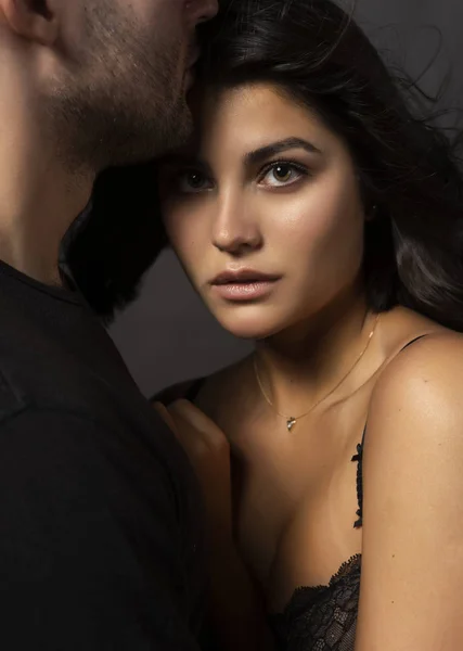 Güzel bir çift portre. Bir adam sensually dudaklarına olan omuz çıplak bir kız alnına dokunuyor. Rahat şık tarzı. Yaşam tarzı, moda, ticari tasarım. Gri arka planı.
