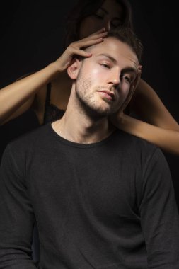 Karanlıkta gizlenmiş seminude kız sadece bir sutyen giyiyor anız yüzünde ile şık bir delikanlı için bir baş masajı yapar. Moda, reklam ve ticari tasarım. Kopya alanı.