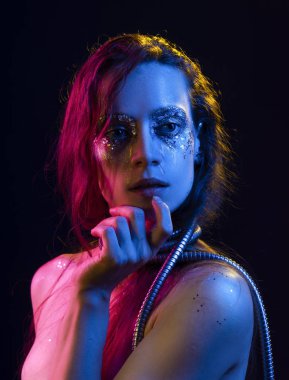 Cretative makyaj güzel kızla glitter yaşlarla, boynunu bir metalik spiral hortum ile pembe, mavi ve sarı ışıkla aydınlatılmış onun yüz tamamladı yaptı. Siyah izole. Kopya alanı.
