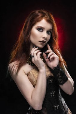 Bir Victorian tarzı steampunk elbise ve korse giyen güzel düşünceli Kızıl cosplay kız. Portre. Siyah ve kırmızı arka plan. Kopya alanı.