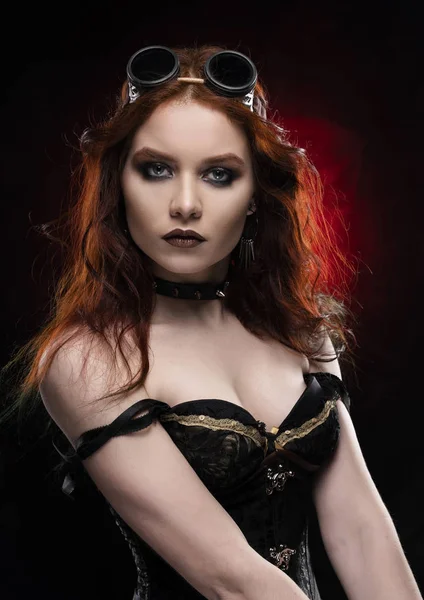 Kırmızı ve siyah arka plan üzerinde derin bir yaka içinde büyük bir meme ile Victorian tarzı steampunk kostüm giyen güzel gülümseyen Kızıl saçlı cosplayer kız. Portre. Kopya alanı.