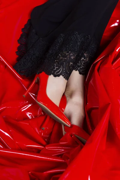 Schöne weibliche Beine in roten Schuhen und schwarzem Kleid mit Spitze an — Stockfoto