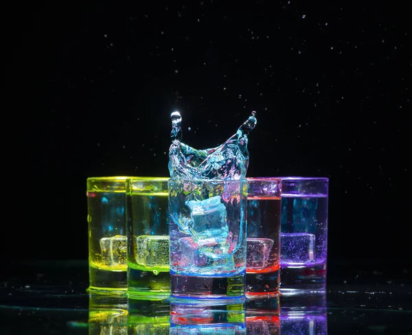 Vasos multicolores llenos de bebidas alcohólicas, con salpicaduras — Foto de Stock