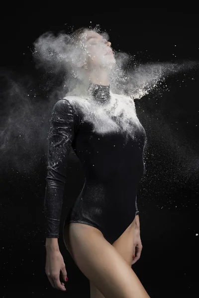 Beautiful slim girl wearing a black gymnastic bodysuit covered w — Stock Photo, Image
