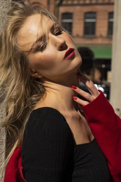 Beautiful blonde girl wearing a red coat and gloves is resting o — Stock Photo, Image