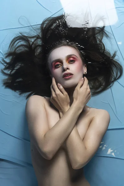 A beautiful naked girl with conceptual makeup in red tones is la