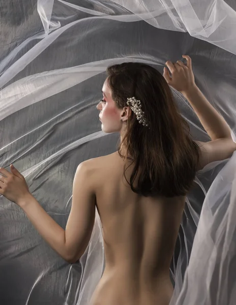 Een mooie slanke topless meisje poses onder de witte stof van een — Stockfoto