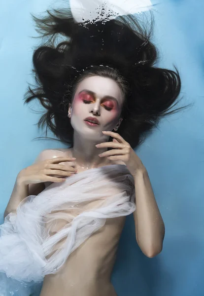 A beautiful naked girl with conceptual makeup in red tones is ly