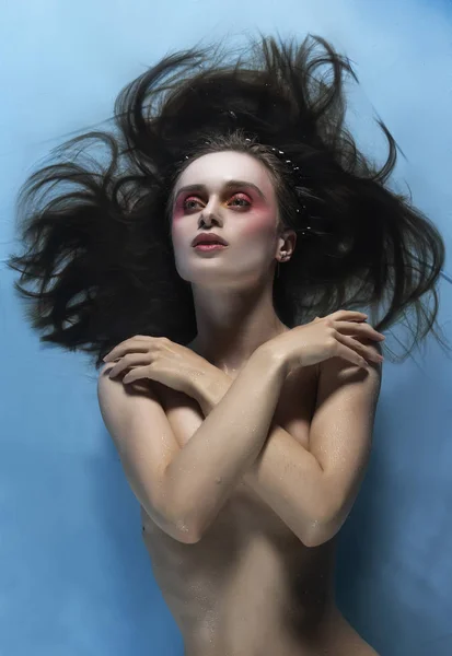 A beautiful naked girl with conceptual makeup in red tones is la