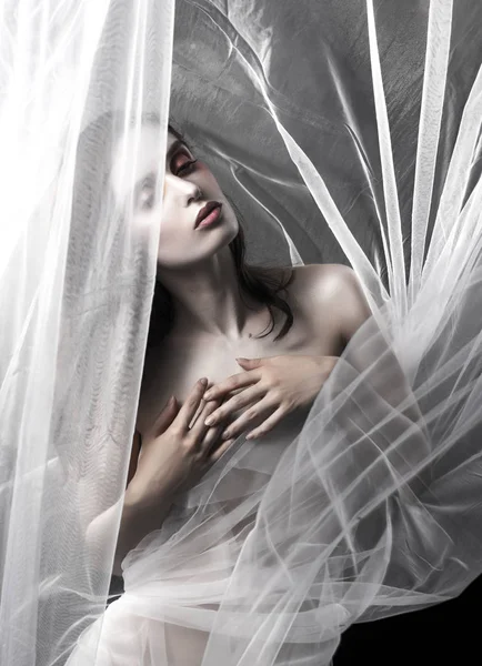 Güzel bir ince üstsüz kız beyaz kumaş arasında pozlar — Stok fotoğraf