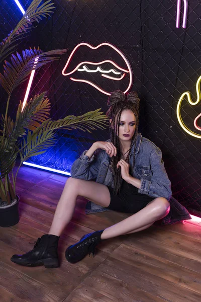 Beautiful girl with a afro cornrows, wearing denim jacket, sits — Stock Photo, Image