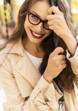 Açık renk ceket, kot pantolon ve gözlük giyen güzel bir kız.