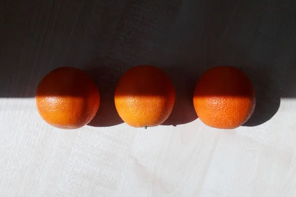 Três Laranjas Estão Uma Mesa Iluminada Pelo Sol Brilhante Manhã — Fotografia de Stock