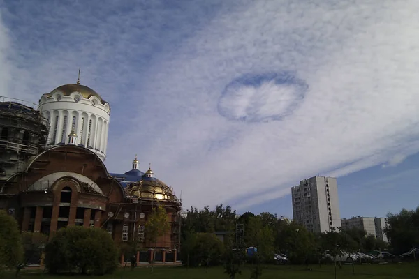 Unusual phenomenon in urban clouds in the sky in the form of a round UFO