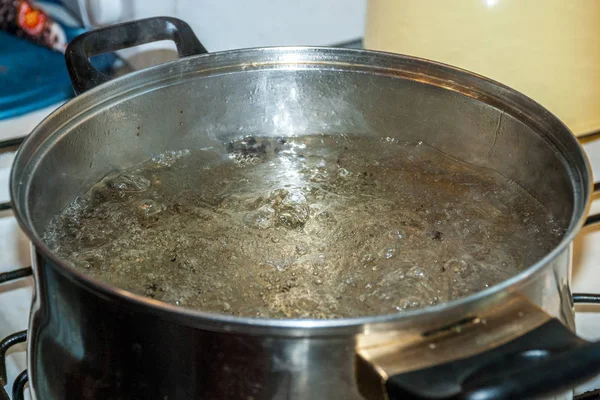 Кипящая вода для спагетти или супа в кастрюле из нержавеющей стали на кухонной плите дома — стоковое фото
