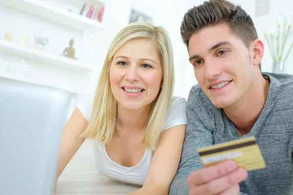 Couple using computer holding a credit card — Stock Photo, Image