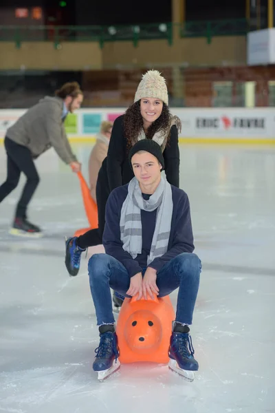 Femme poussant un homme pendant le patin à glace — Photo