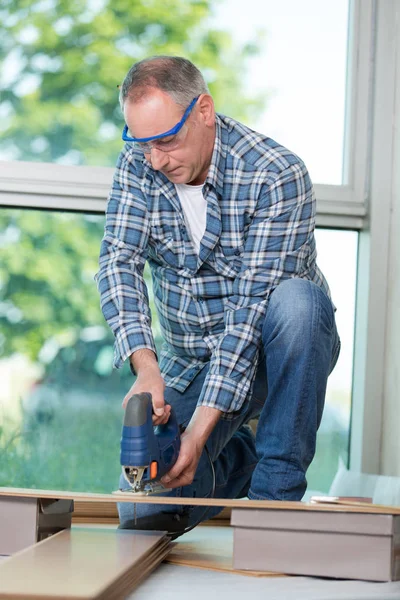 Menuisier sénior coupant le bois avec scie à ruban sur le chantier — Photo