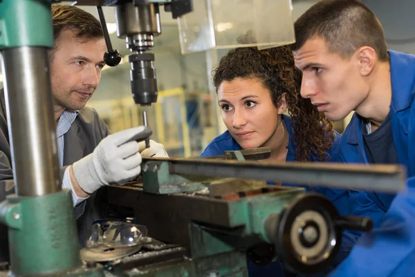 Apprentice engineer working on drill in factory — Stock Photo, Image