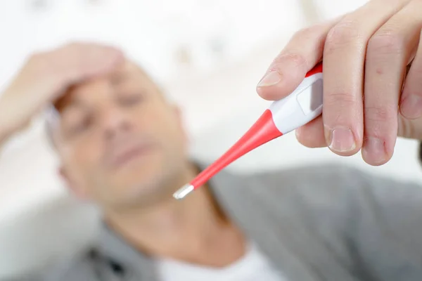 Zbliżenie: chory człowiek trzyma termometr — Zdjęcie stockowe