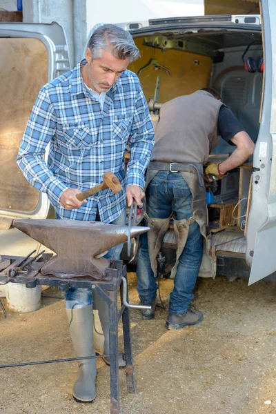 Blacksmith working outdoors and man — Stock Photo, Image