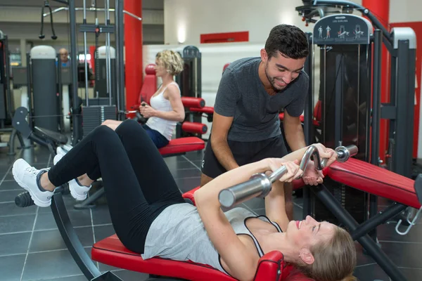 Personlig tränare hjälpa ung kvinna i gymmet — Stockfoto