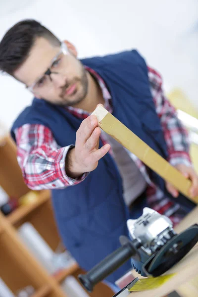 Workman holding tejp, vinkelslip på bänk — Stockfoto