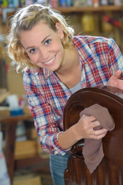 Femme heureuse essuyant la poussière des meubles en bois — Photo