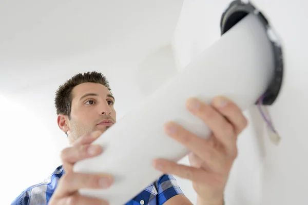 Elektricien zorgvuldig ter vervanging van een licht — Stockfoto