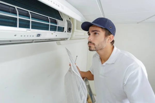 Porträt eines erwachsenen Technikers, der eine Klimaanlage repariert — Stockfoto