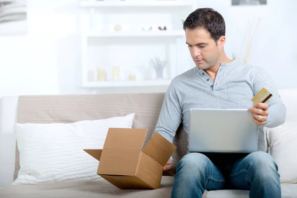 Handsome male online shopping with parcel received and credit card — Stock Photo, Image