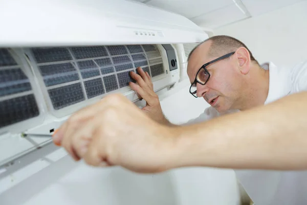 Técnico masculino feliz reparación de aire acondicionado con destornillador —  Fotos de Stock