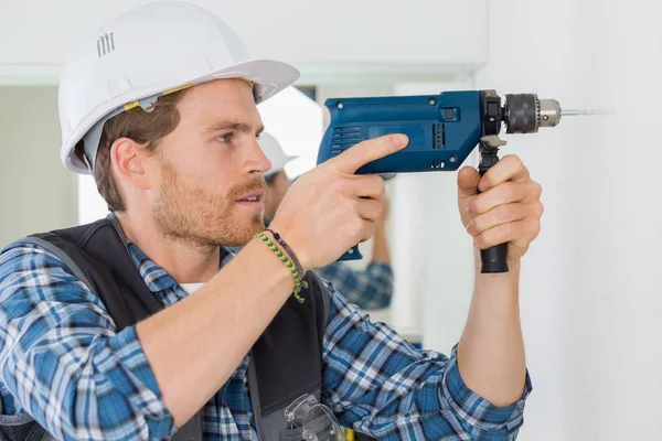 Junge hübsche Handwerker mit einem Bohrer bei der Arbeit — Stockfoto