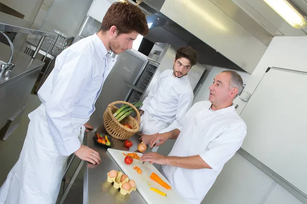 Chefe e seus assistentes chooping legumes — Fotografia de Stock