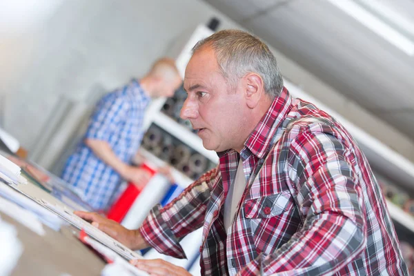 Portrait of male designer with blueprints at desk — Stock Photo, Image