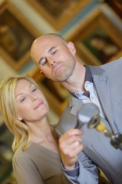 Mature couple reviewing item at auction place — Stock Photo, Image