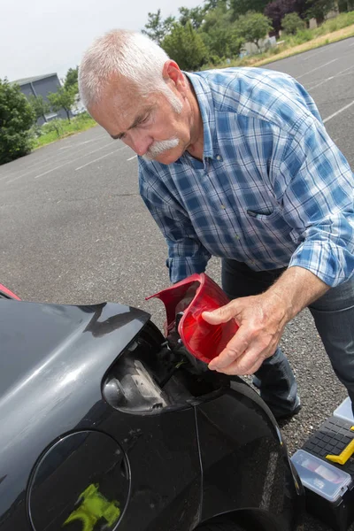 Alter Mann installiert Rücklicht am Fahrzeug — Stockfoto