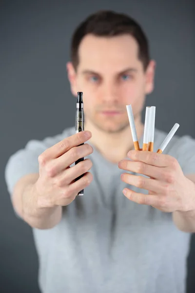 Mann vergleicht klassische Tabakzigarette und elektronische Zigarette — Stockfoto