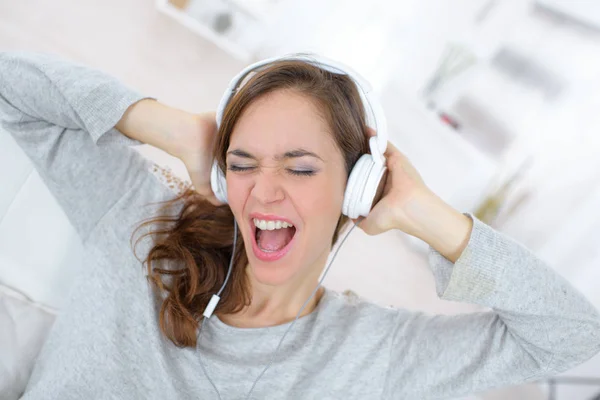 Jovem mulher ouvindo música em fones de ouvido e canta — Fotografia de Stock