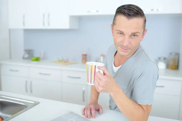 Joven sonriendo y sosteniendo una taza de té — Foto de Stock