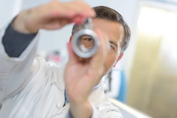 Ophthalmologist examines the eyes with handheld lense — Stock Photo, Image