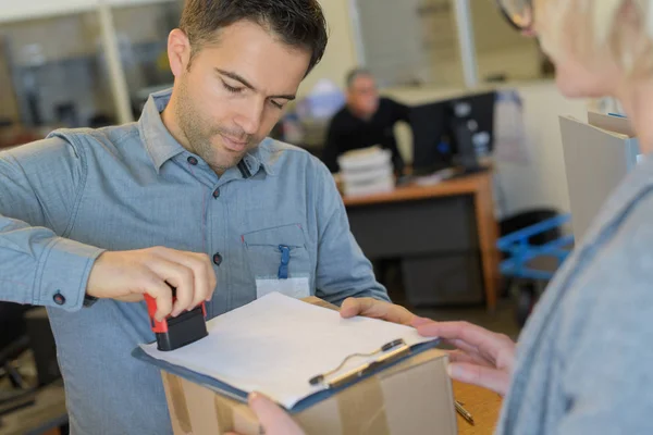 Employee stamping document given by delivery man — Stock Photo, Image