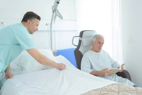 Ondersteunende verpleegkundige maken van patiënt bed — Stockfoto