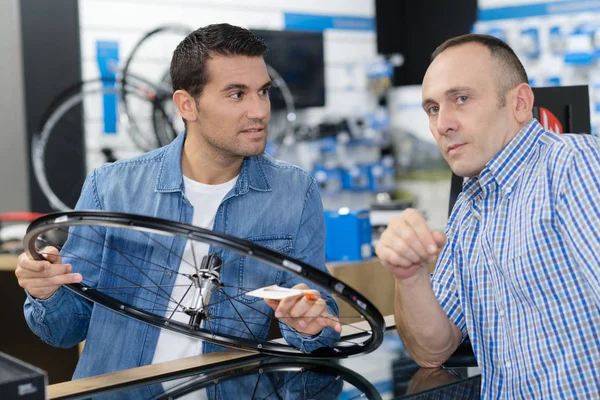 Hombre sosteniendo nueva rueda de bicicleta en las manos en la tienda — Foto de Stock