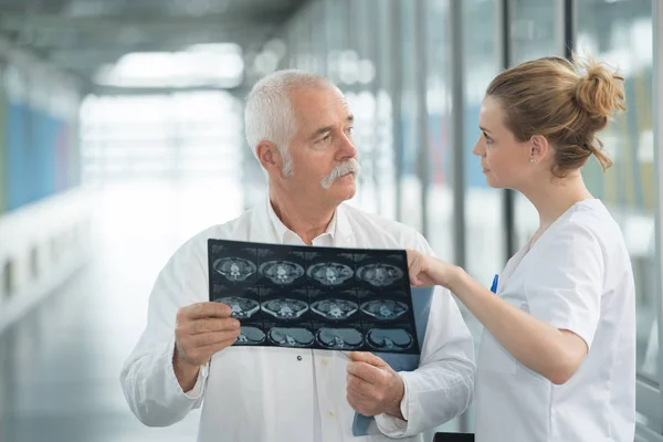 Equipe médica discutindo raios-x no corredor hospitalar — Fotografia de Stock