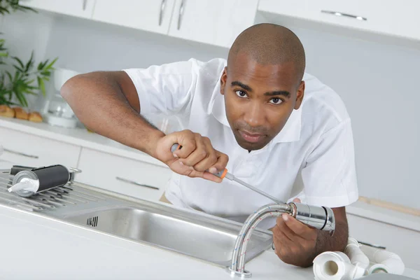 Plombier travaillant sur le robinet de cuisine — Photo